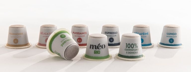 Neuf capsules de café compostables étiquetées avec différents types tels que « Harmonie », « Délicatesse », « Espresso » et « Décaféiné » sont disposées sur une surface blanche.