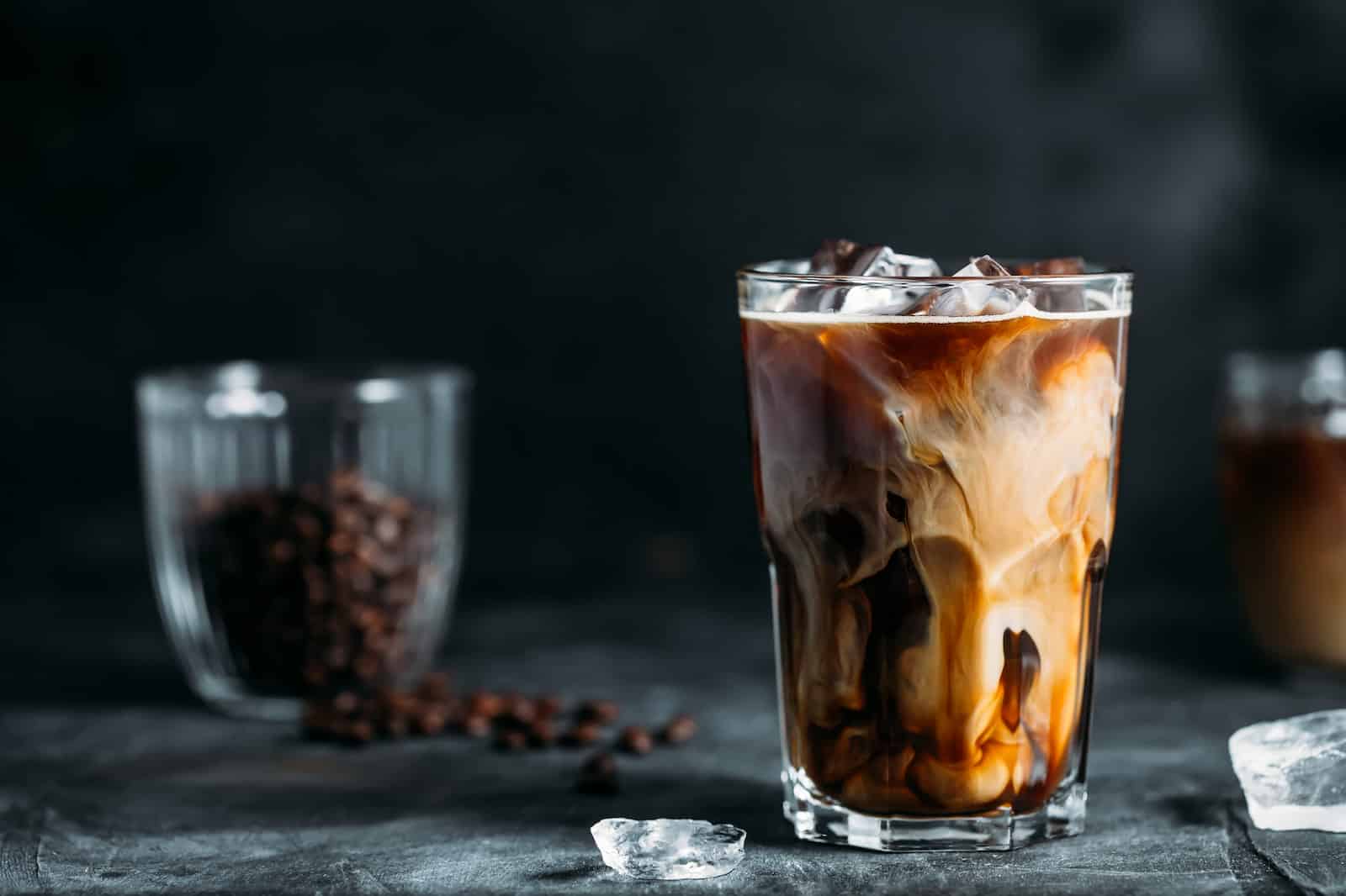 lait verse dans du cafe glace table sombre 1