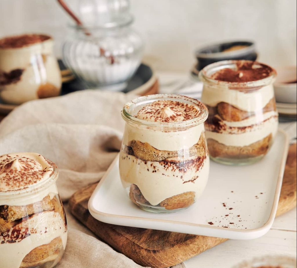 vertical shot delicious tiramisu little glasses with powder white table (1)