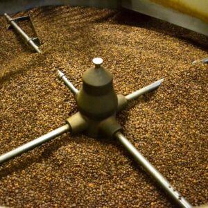 machine cylindrique remplie de grains de café torréfiés avec bras rotatifs