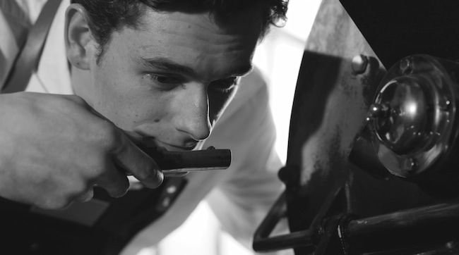 une personne inspectant attentivement une pièce de machine, en se concentrant intensément sur elle.