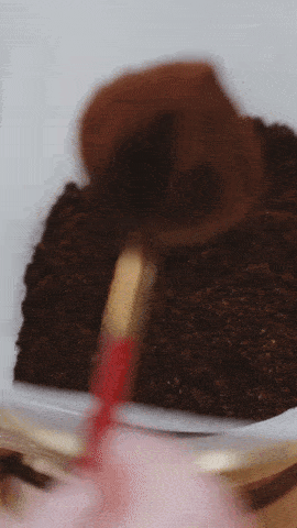 une main utilise une cuillère pour prélever du café moulu dans un récipient.